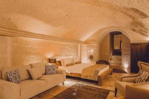 Nino Cave Suites في أوروغوب: غرفة نوم بسرير واريكة في غرفة