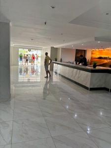 un hombre caminando en un vestíbulo con un mostrador en Via Venetto Flat en Fortaleza