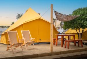 a tent with chairs and a table in front of it at Glamping Camp Faro in Faro