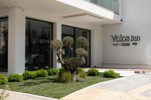 un bâtiment avec un arbre devant un bâtiment dans l'établissement Volos Inn Hotel, à Vólos