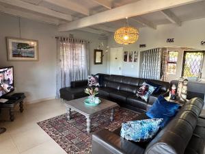 a living room with a leather couch and a table at Big Fish Seaside Cottage, Sleeps 10 Guests in 5 Bedrooms in Port Edward