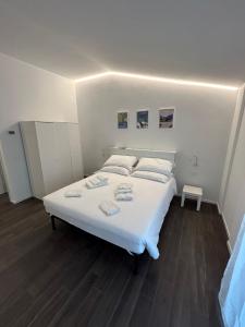 een groot wit bed in een kamer met houten vloeren bij Lake Home Apartments in Lipomo