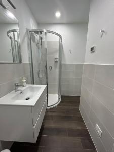 een witte badkamer met een douche en een wastafel bij Lake Home Apartments in Lipomo