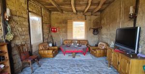 BorintsiにあるКъща за гости Светулките Fireflies Guest Houseのテーブルとテレビのあるリビングルーム