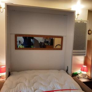 espejo sobre una cama en un dormitorio en FACE ECOLE DE VOILE LA PLAGE A 50 metres, en Bernières-sur-Mer