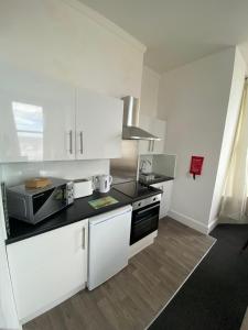 a kitchen with white cabinets and a black counter top at Farina No4, Sea view apartment sleeping 4 guests in Bridlington