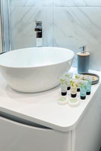 baño con lavabo blanco y 4 botellas de crema hidratante en Modern Comfort Two Bedrooms Flat, Coulsdon CR5, en Coulsdon