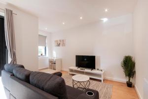 a living room with a couch and a tv at Modern Comfort Two Bedrooms Flat, Coulsdon CR5 in Coulsdon