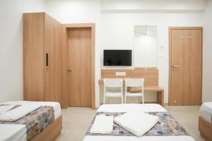 1 dormitorio con 2 camas y escritorio con TV en Maruti Grand Hotel, en Rajkot