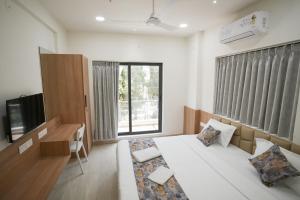 Maruti Grand Hotel في راجكوت: غرفة نوم بسرير ومكتب وتلفزيون