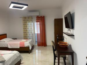 a bedroom with two beds and a table and a television at Vila C++ in Berat