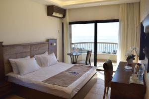a bedroom with a bed and a desk and a balcony at Sands Hotel in Jbeil