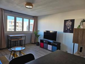 een woonkamer met een tv en een tafel bij Appartement Art deco proche bords de Marne in Neuilly-sur-Marne