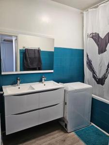 een badkamer met 2 wastafels en een douchegordijn bij Appartement Art deco proche bords de Marne in Neuilly-sur-Marne