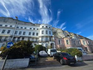 a white building with a hill behind it at Studio next to port, cliffs, with parking in Kent