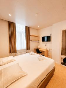 a bedroom with a large white bed and a desk at Alpha Hotel in Ostend