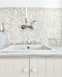 a sink in a kitchen with a wall of shells at Cabarnus House in Parikia