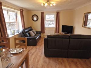 a living room with a black couch and a television at Beaumont Court in Coventry