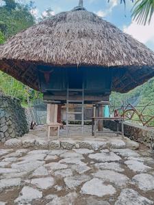 uma cabana com um guarda-chuva de palha e uma cadeira em Agamang Traditional House Inn em Banaue