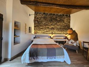 1 dormitorio con cama y pared de piedra en Viña Candaz, en Taboada