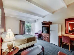 a hotel room with a bed a desk and a refrigerator at Red Carpet INN Whippany in Whippany