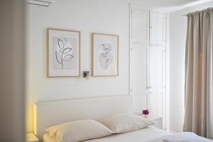 a white bedroom with two framed drawings on the wall at Near old town apartment with free parking and air condition in each room in Zadar
