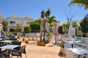 un restaurante con mesas, sillas y sombrillas en The Palms Golf Del Sur - Casa Andromeda en San Miguel de Abona