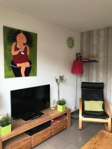uma sala de estar com uma televisão de ecrã plano e uma cadeira em Fewo Klimduin Castricum em Castricum