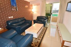 Il comprend un salon doté d'un mobilier en cuir bleu et d'un mur en briques. dans l'établissement Adamaoua Grand Hôtel Aéroport, à Douala