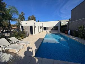a swimming pool with chairs and a house at Departamento Amoblado de lujo! in Pilar