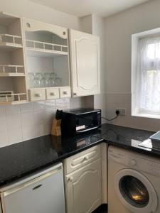 a kitchen with a washing machine and a microwave at 1 Bedroom Flat Apartment Bromley in Bromley