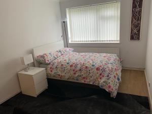 a bedroom with a bed with a floral bedspread and a window at 1 Bedroom Flat Apartment Bromley in Bromley