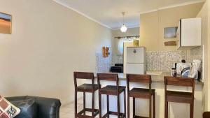 a kitchen with four chairs and a counter with a refrigerator at Huis KlipdriftSelf Catering &B&B in Hentiesbaai