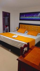 ピタリトにあるHOTEL NAPOLESのベッドルーム1室(大型ベッド1台、オレンジ色のベッドカバー付)