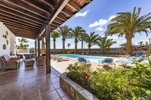 an outdoor patio with a pool and palm trees at Casa Palmeral in Mácher
