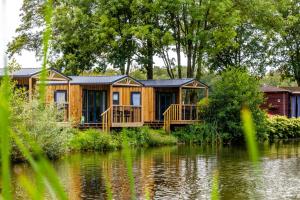 a wooden cabin on the side of a lake at Vakantiepark Vlinderloo in Enschede