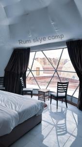 a bedroom with a bed and two chairs and a window at Rum Skye camp in Wadi Rum