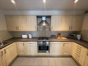 a kitchen with wooden cabinets and a stove top oven at Childes Court in Nuneaton