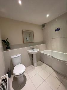a bathroom with a toilet and a sink and a tub at Childes Court in Nuneaton