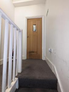 an empty hallway with a wooden door and stairs at Stepney Green Self Contained Studio in London