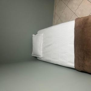 a white bed with a pillow in a room at apart hotel big john 102 in Divinópolis +24 photos