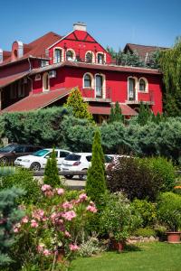 a red building with cars parked in front of it at Hotel Szent István in Eger