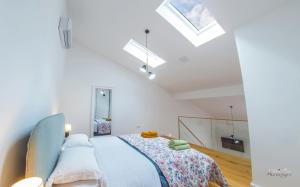una camera bianca con letto e lucernari di Apartments Gallery M and A - with pool a Mostar
