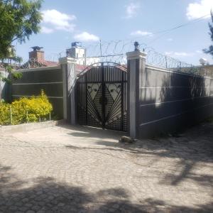 亞的斯亞貝巴的住宿－Guest House at the center of Addis Ababa.，通往带栅栏的房子的门