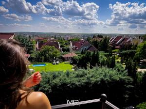 a woman standing on a balcony looking at a house at Hotel Szent István in Eger