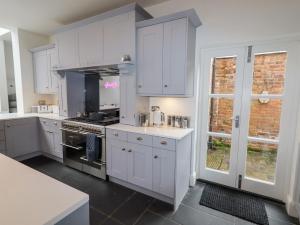 eine Küche mit weißen Schränken und einem Herd in der Unterkunft Anglesey House in Nantwich