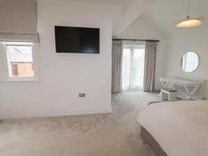 a bedroom with a bed and a tv on the wall at Anglesey House in Nantwich