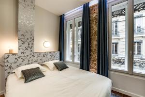 a bedroom with a white bed and two windows at Les Jacobins, hypercentre in Lyon