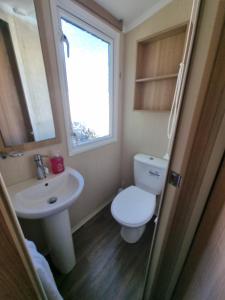 ein Bad mit einem WC, einem Waschbecken und einem Fenster in der Unterkunft Stunning modern lodge in Port Seton