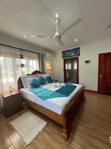ein Schlafzimmer mit einem großen Bett mit blauen Kissen in der Unterkunft Benjamine's Guesthouse in La Digue